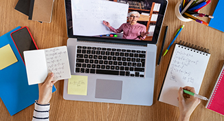Image of Person watching video whilst taking notes